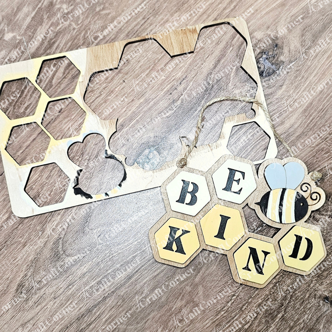 Janet's Craft Corner's "Be Kind Kids Pop-Out" features wooden hexagon pieces forming a honeycomb design with "BE KIND" and a bee illustration, ideal for wall hanging. A nearby DIY craft kit stencil offers hexagon cutouts for creative projects on wood surfaces.