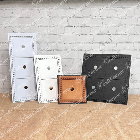 Four Heartland Bead Trim Swappable Squares Frames for switches or outlets, each with scalloped edges and round openings, are shown upright on burlap against a white brick wall in white, cream, brown, and black.