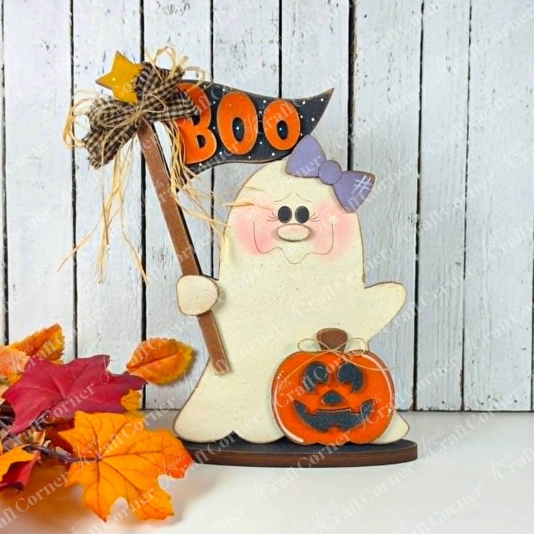 Add a playful touch to your spooky-cute décor with the Boo Ghostie Shelf Sitter DIY home decor craft kit from Janet’s Craft Corner. This adorable Halloween shelf sitter features a ghost with a purple bow holding a “BOO” sign, standing beside a cheerful jack-o’-lantern. Autumn leaves are scattered at its feet, all set against a rustic white wooden background – perfect for brightening up your festive display!.