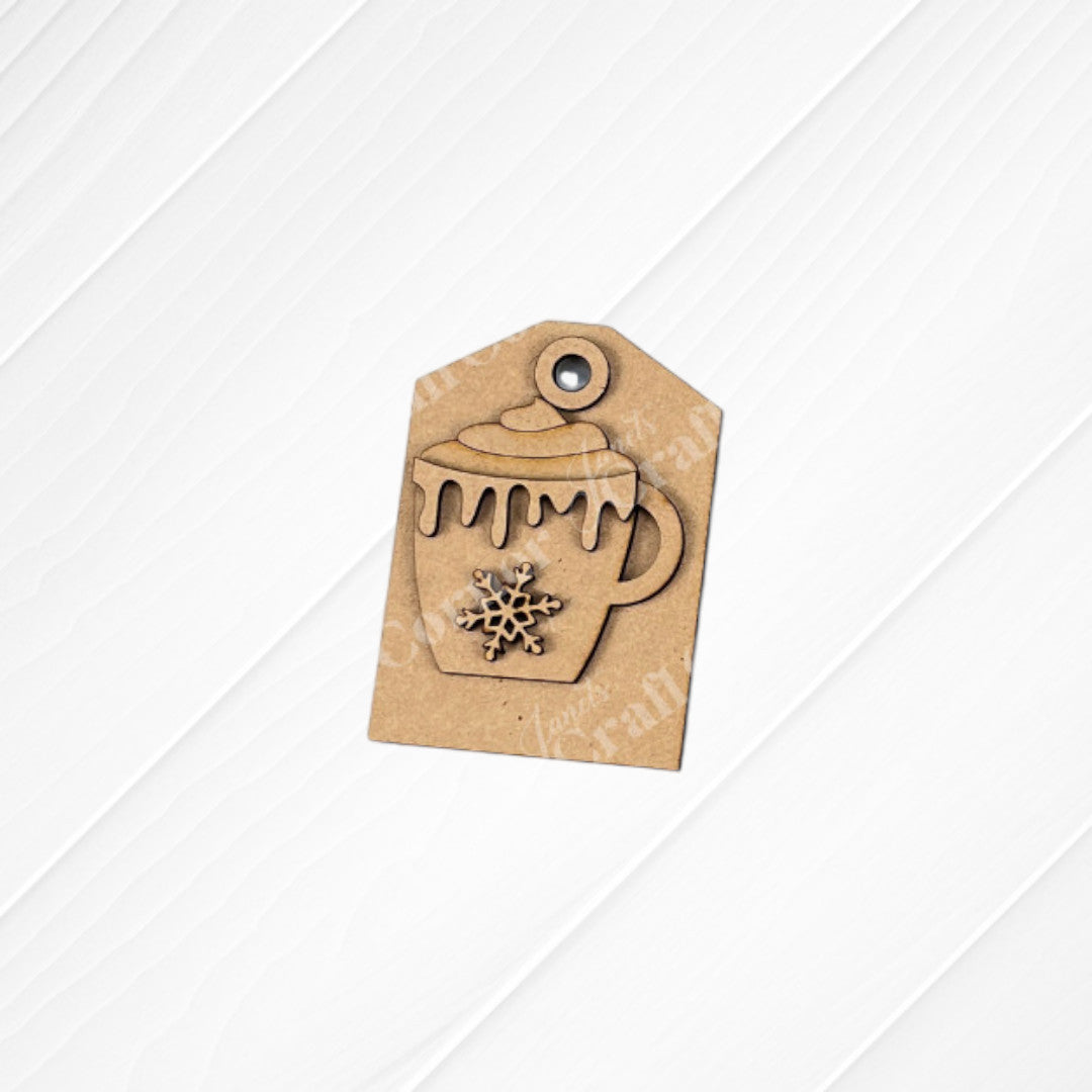 Janet's Craft Corner Cup of Cheer Hot Cocoa Mini Shelf Sitters DIY craft kit features a brown tag with a mug cutout, dripping icing, and snowflake detail—perfect seasonal decor on a white wooden background. Set of 1.
