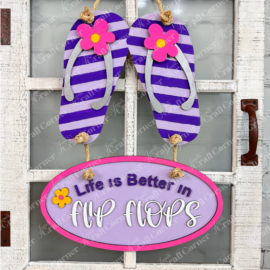 Janet's Craft Corner Flip Flops Door Hanger - Summer DIY Craft Kit (13.5" x 11") features purple and white striped flip-flops with pink flowers above an oval sign reading "Life is better in flip flops"—ideal for beach-themed decor.