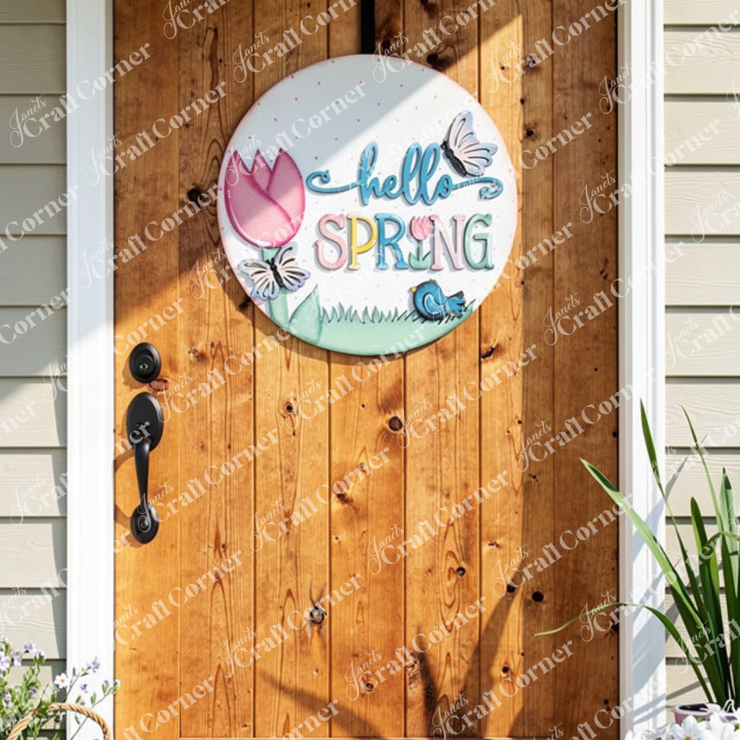 Add a touch of seasonal charm to your home's décor with Janet's Craft Corner's "Hello Spring" Round Door Hanger. This delightful DIY kit features vibrant letters, a tulip, butterflies, and a bird resting on grass. It easily hangs against a wooden door with a plant nearby, making it the perfect addition for welcoming springtime.