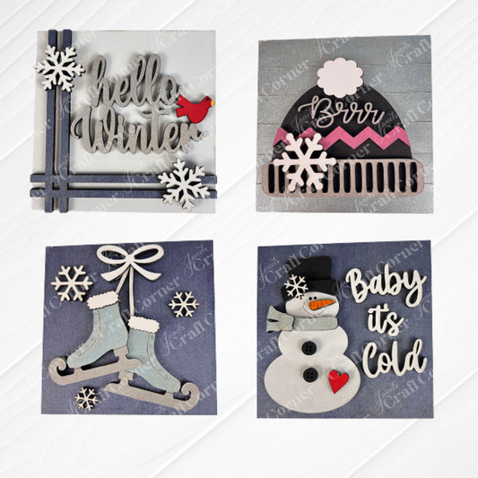 Janet's Craft Corner's Hello Winter Squares set includes four winter-themed tiered tray signs: "Hello Winter" with snowflakes and a red bird, a "Brrr" hat, ice skates, and a snowman—ideal for seasonal decor or DIY crafting.