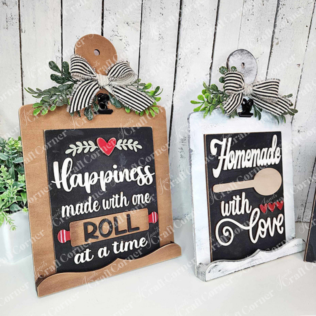 Janet's Craft Corner Kitchen Switchable Farmhouse Signs DIY kit lets you create rustic kitchen decor—one sign reads "Happiness made with one roll at a time," the other, "Homemade with love" (with spoon and hearts). Set of 1 included.