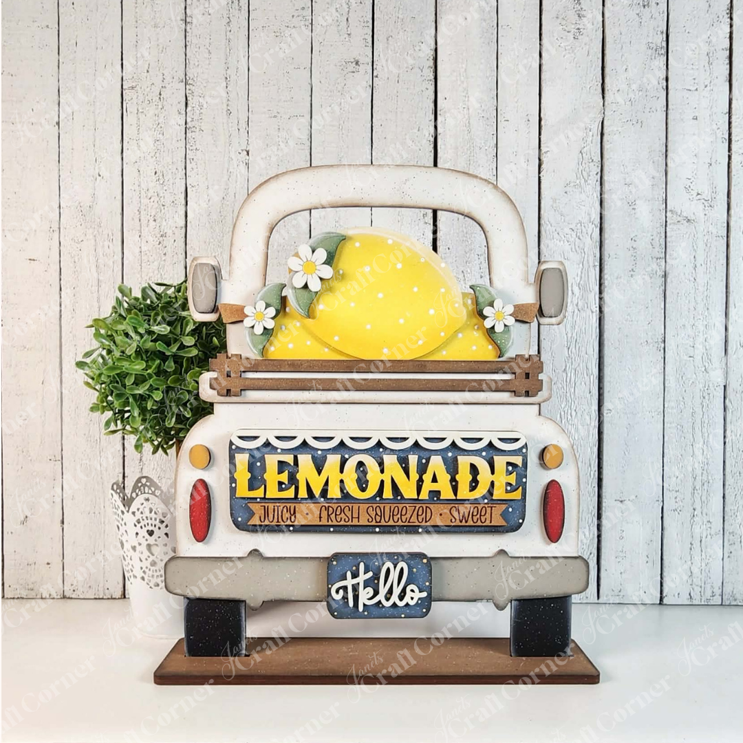 The Lemon Interchangeable Insert by Janet's Craft Corner is a DIY seasonal home decor kit with 3 unfinished wood pieces, shaped like a vintage truck, featuring a lemon and daisies with “LEMONADE” and “Hello” text—perfect for creative decorating projects.