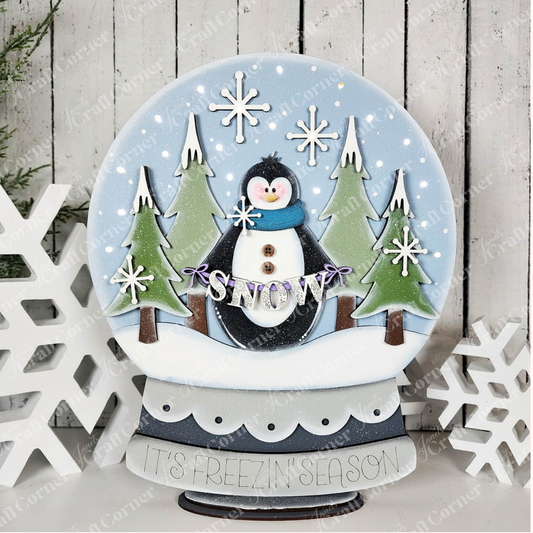Bring festive cheer to your home with the Penguin Snowglobe Shelf Sitter DIY home decor craft kit from Janet’s Craft Corner. This delightful set features a charming penguin wearing a blue scarf, surrounded by trees and swirling snowflakes. A cheerful “SNOW” banner brightens the scene, while the base reads “IT’S FREEZIN’ SEASON.” Finished with a white snowflake decoration beside it, this easy-to-make holiday accent adds whimsical charm to any space.