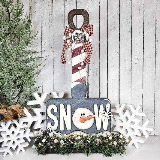 Add a charming winter touch to your home with Janet's Craft Corner Winter Snow Shovel Shelf Sitter DIY craft kit—featuring "SNOW" with a snowman "O," pine garland, and snowflakes for perfect seasonal décor. Set of 1.