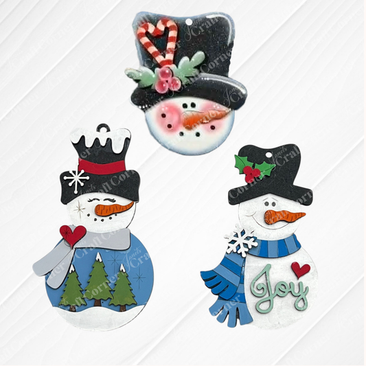 Bring winter cheer to your holiday decor with Janet’s Craft Corner Sweet Winter Snowmen Ornaments—a DIY holiday craft kit featuring your choice of three enchanting designs: one snowman with a candy cane hat, another with trees and a heart, and a third holding a “Joy” sign and wearing a scarf. Each ornament is displayed on a white wooden background, making them perfect for festive decorating or your next winter crafting project.