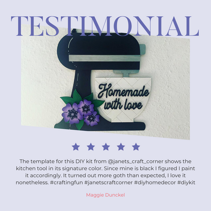 Janet's Craft Corner offers a Kitchen Mixer Wall Hanger DIY Kit, featuring a black mixer silhouette with "Homemade with love," and purple flowers, enhanced by Maggie Dunckel's painting testimonial. Perfect for cooking-inspired decor. #KitchenDecor #DIYCrafts #HomeInspiration.