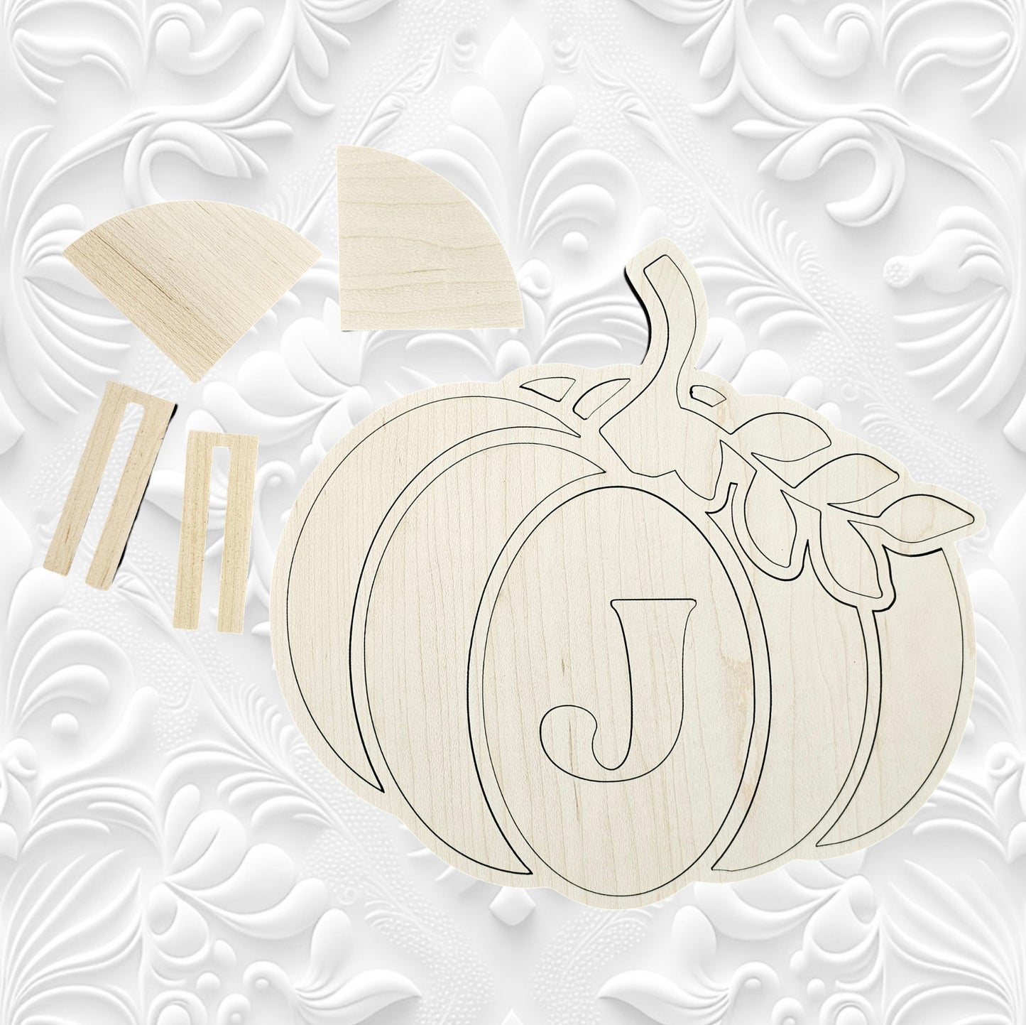 Janet's Craft Corner presents the Monogram Pumpkin Shelf Sitter, a DIY home decor craft kit featuring a wooden pumpkin engraved with the letter "J." This set includes various components for assembly, ideal for crafting personalized decorations. The backdrop highlights an elegant white embossed floral pattern.