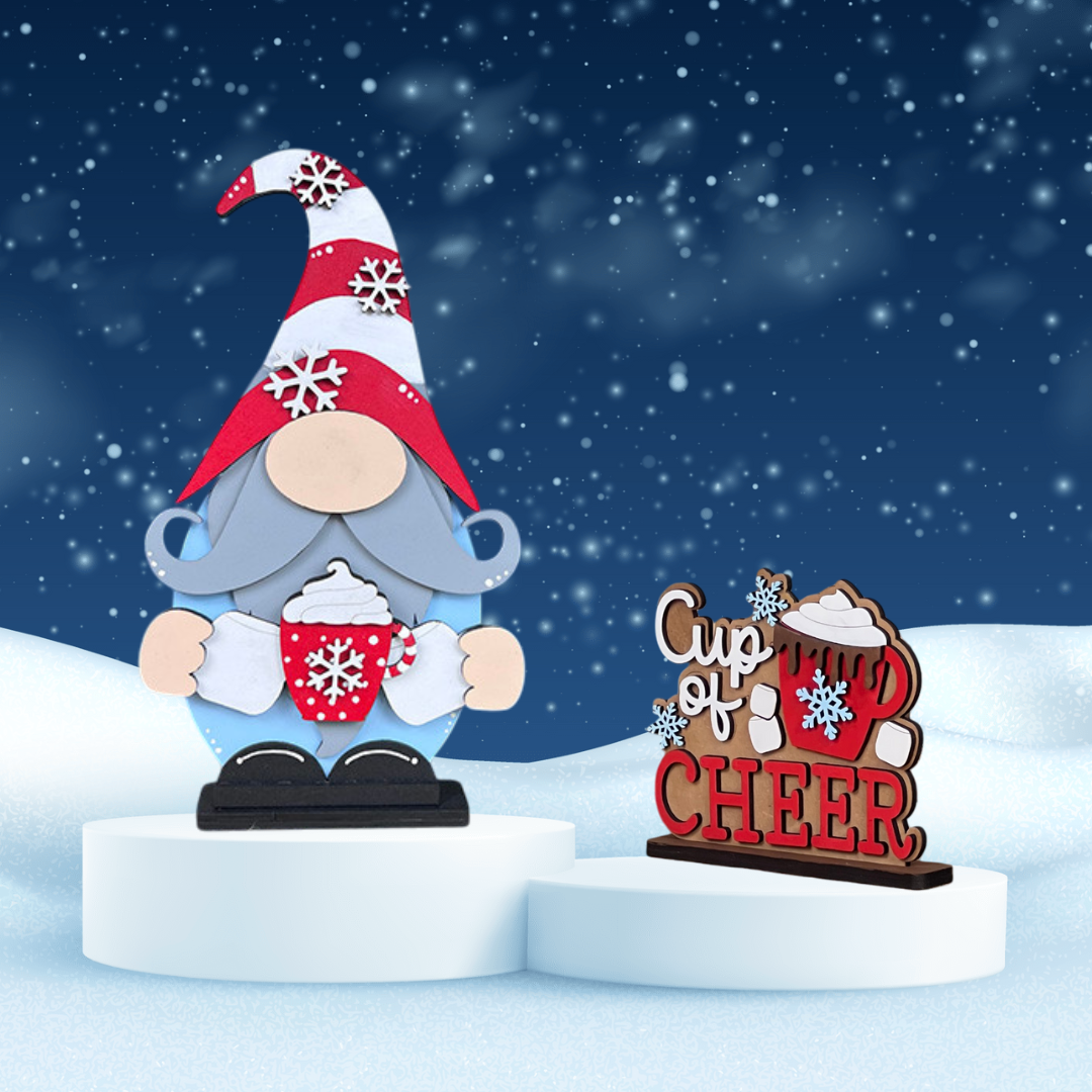 The "Hot Cocoa Gnome Shelf Sitter" from Janet's Craft Corner is a DIY decor kit featuring a gnome with a red-and-white hat holding cocoa. A "Cup of CHEER" sign with snowflakes adds festive charm, perfect against a starry, snowy backdrop for holiday home decor.