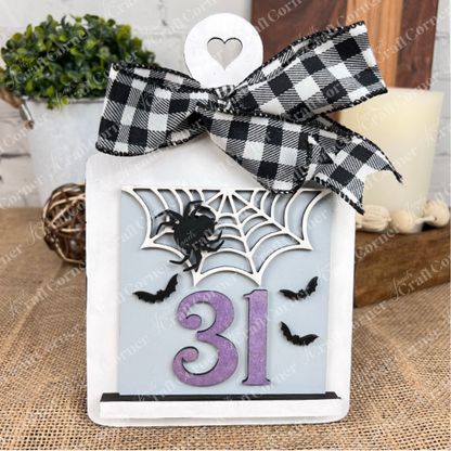 The Oct 31 Squares by Janet's Craft Corner is a Halloween sign featuring a black-and-white checkered bow, spider web, two bats, and purple "31." Ideal as festive tiered tray decor for your home.
