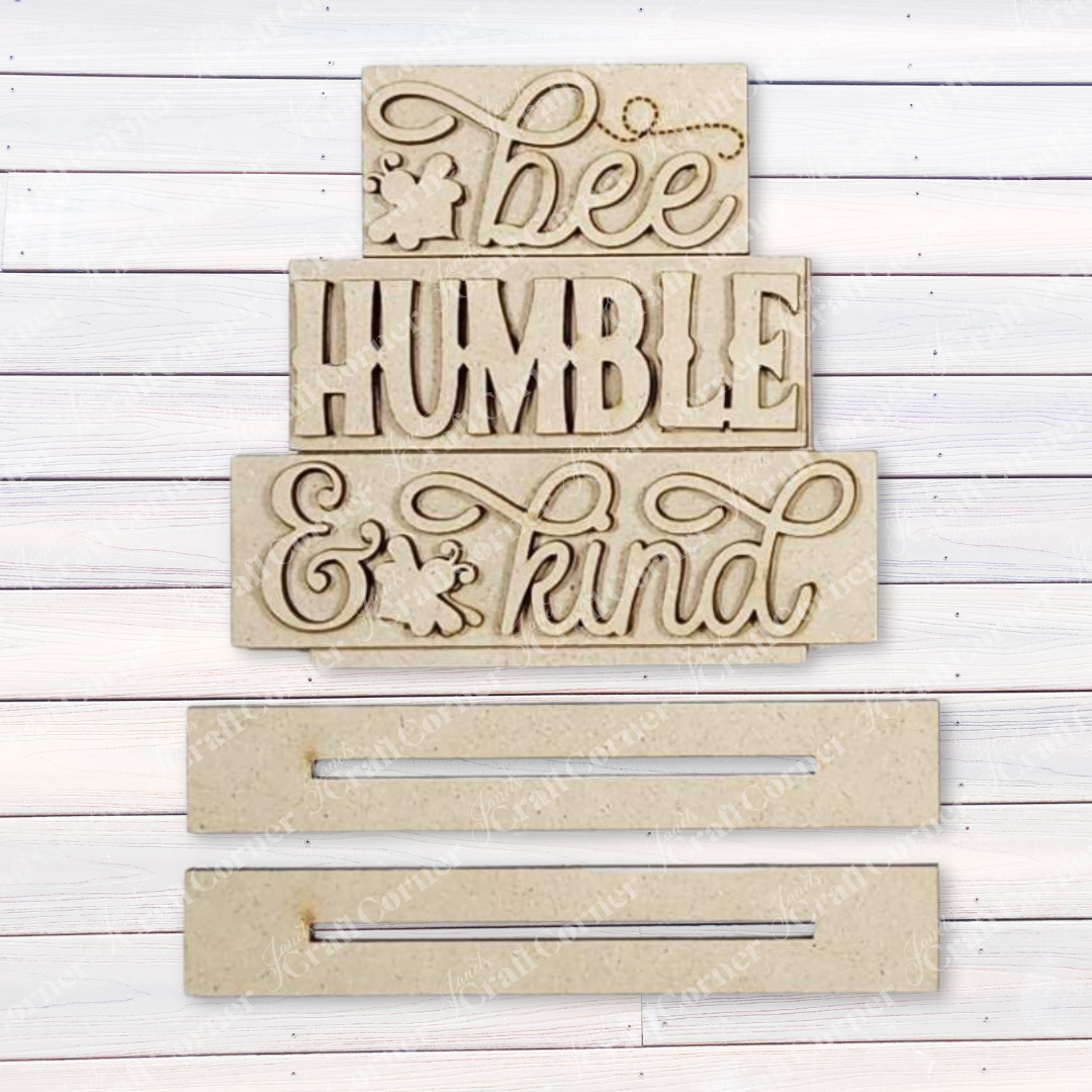 Janet's Craft Corner offers the Honey Bee Mini Shelf Sitter Set, a DIY seasonal home decor kit featuring wooden plaques with "bee HUMBLE & kind" against a white background and adorned with a small bee icon. Perfect for bee-lovers, it adds charm to any space.