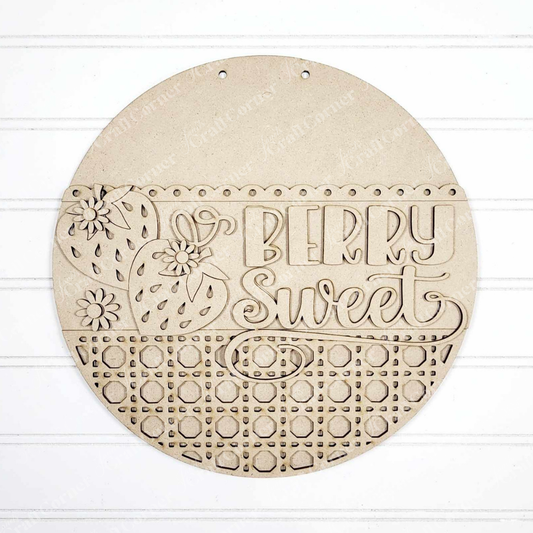 The Berry Sweet Wall Hanger by Janet's Craft Corner is a round wooden decoration with carved strawberries, flowers, and playful "Berry Sweet" text. The lower half features circular cutouts, placed beautifully on a white textured surface.