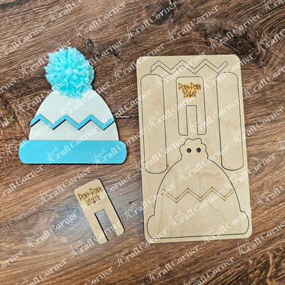 Discover Janet's Craft Corner's "Build a Beanie Pop-Out," a hand-painted crafting template for a winter hat with a blue pom-pom, rustic wooden surface, charming zigzag patterns, and detailed instructions for delightful home décor assembly.