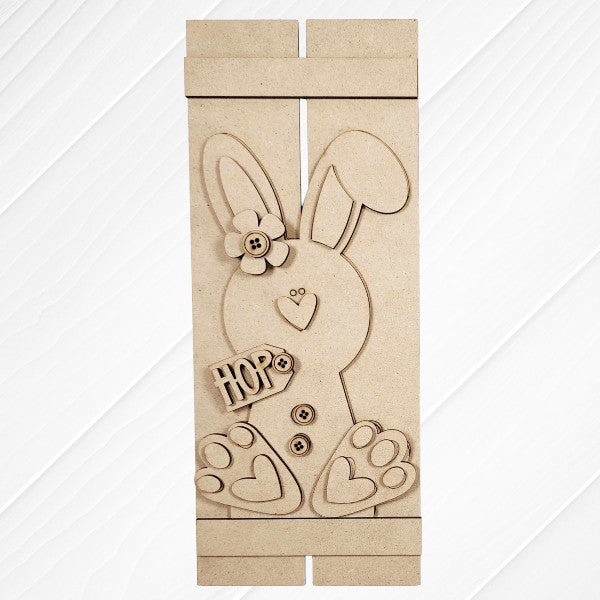 The Bunny Table Top Pallet by Janet's Craft Corner is a charming DIY home decor craft kit featuring a wooden bunny with a flower, buttons, and heart-shaped foot details. Displayed on a white textured surface, it spells "HOP" and makes an ideal shelf leaner.