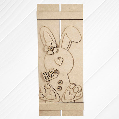 The Bunny Table Top Pallet by Janet's Craft Corner is a charming DIY home decor craft kit featuring a wooden bunny with a flower, buttons, and heart-shaped foot details. Displayed on a white textured surface, it spells "HOP" and makes an ideal shelf leaner.