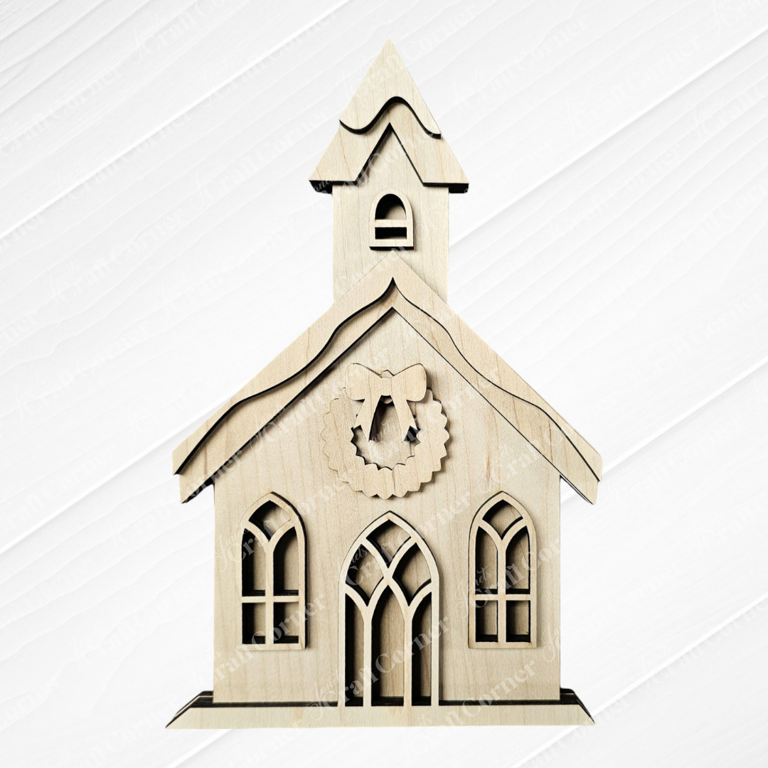 The Christmas Village Shelf Sitters - Set of 4 by Janet's Craft Corner includes a charming wooden model of a small church, ideal for your holiday display. It boasts a steeple, arched windows, and a decorative wreath above the entrance, all set against a pristine white background.