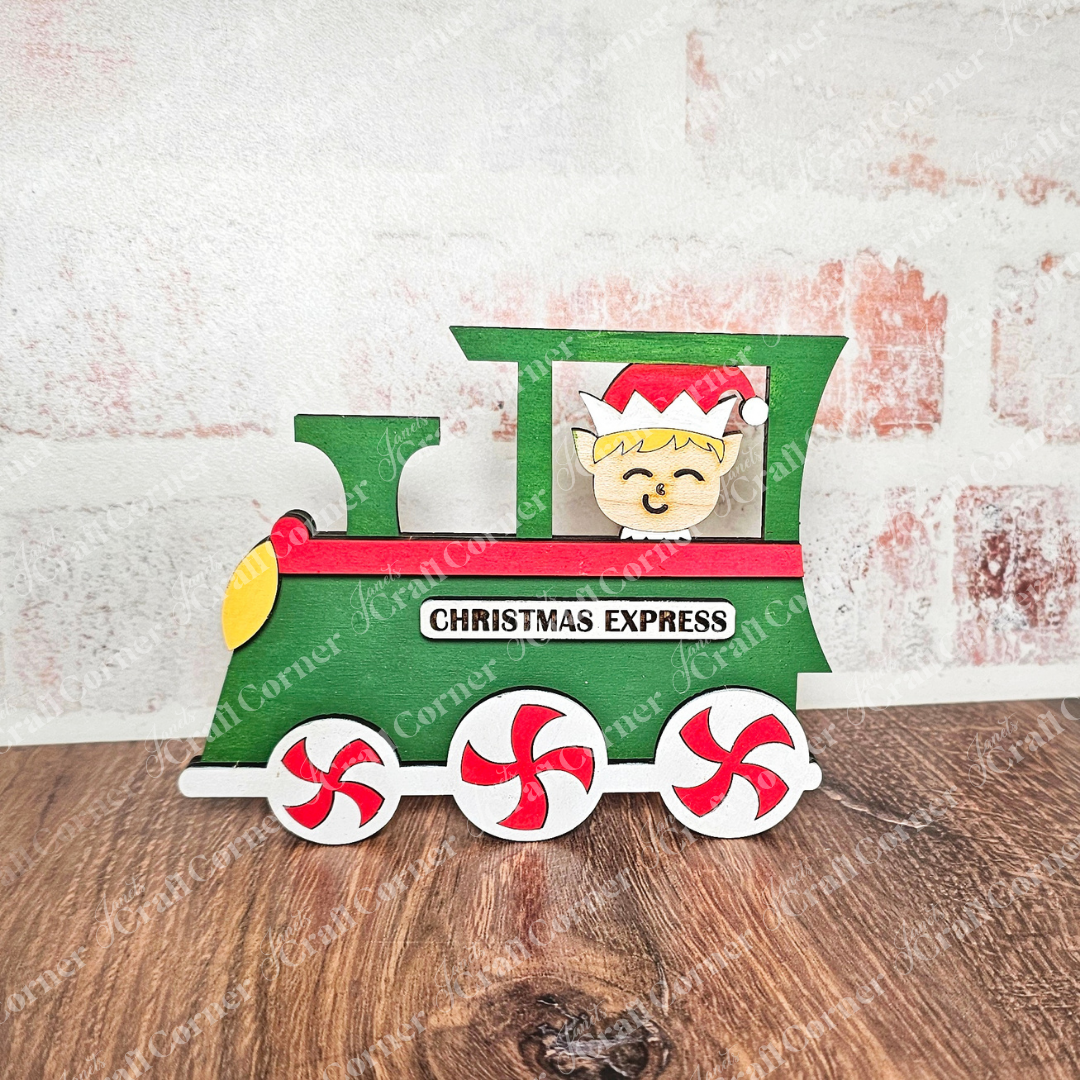 The "Elf Train Kids Pop-Out | Early Access" from Janet's Craft Corner features a decorative wooden train engine known as the "Christmas Express," complete with a friendly elf peeking out. This green train is ideal for children’s DIY projects, featuring red and white peppermint swirl wheels set against a brick-patterned background, making it both fun and beneficial for enhancing fine motor skills development.