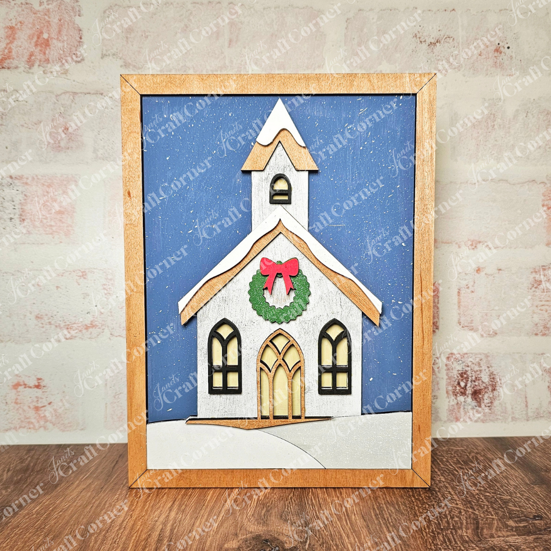 Introducing the Framed Church Sign Shelf Leaner DIY Craft Kit from Janet's Craft Corner. This kit allows you to create a charming hand-painted scene featuring a snow-covered church on a blue background, adorned with a festive wreath and red bow. With its subtle snow effect and wooden frame, this piece adds personalized charm to your home décor.