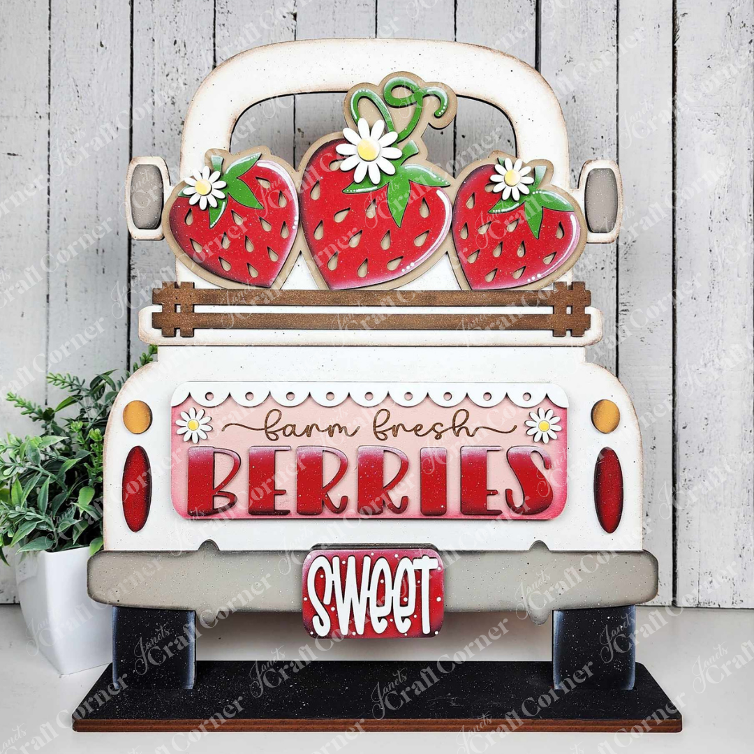 The Fresh Berries Interchangeable Insert from Janet's Craft Corner is a 3-piece DIY home decor kit featuring a white vintage truck with strawberries and flowers, reading "farm fresh BERRIES" and "SWEET" on a rustic wood-look background—perfect for summer decorating.