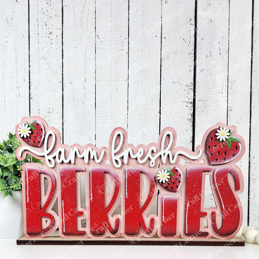 The Fresh Berries Word Art Shelf Sitter DIY kit from Janet's Craft Corner features "farm fresh BERRIES" in bold red letters, strawberries, and daisies on a white wood background—a delightful cut-out to decorate your home.
