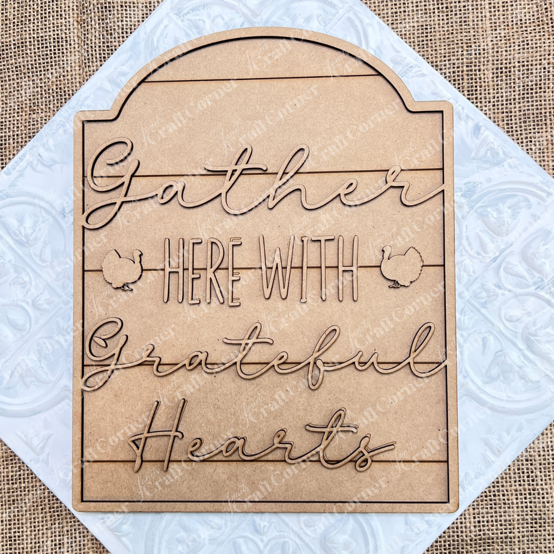 The Grateful Hearts Shelf Leaner DIY home decor craft kit by Janet's Craft Corner is an inviting addition to any space. It features cursive text that reads, "Gather here with grateful hearts," accompanied by two small chicken silhouettes on a rustic burlap background, making it perfect for home décor.