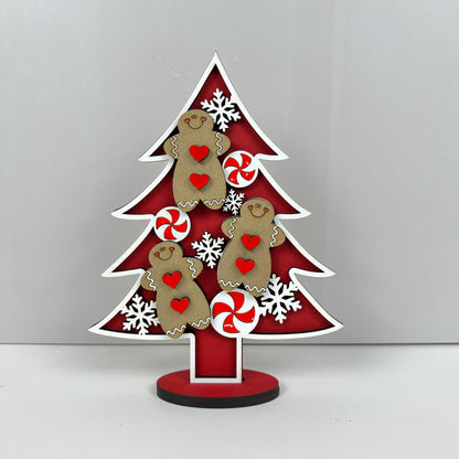 The Standing Christmas Tree Shelf Sitters from Janet's Craft Corner make delightful holiday decor, showcasing gingerbread figures, red and white peppermint swirls, snowflakes, and red hearts set against a vibrant red background—ideal for bringing festive cheer to any shelf display.