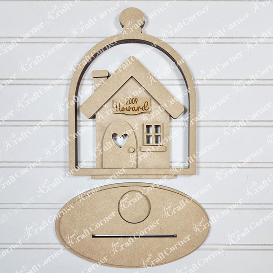 The "Home Cloche Votive Holder Shelf Sitter" by Janet's Craft Corner is a wooden cutout of a house engraved with "2009 Howard," set in a cloche-shaped frame. It features an oval plaque against a lined white background, perfect for DIY craft kit enthusiasts seeking unique home decor.