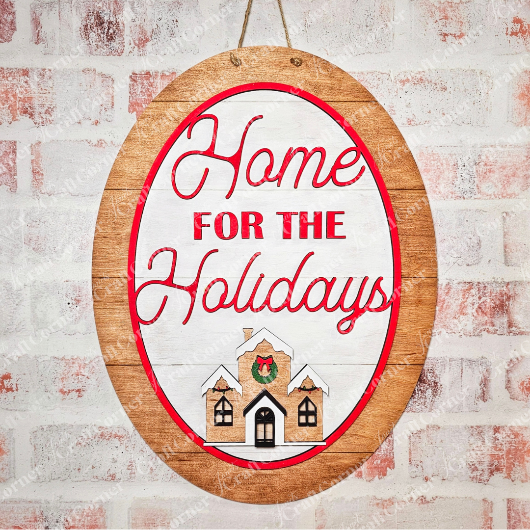 A wall adorned with a hand-painted "Home for the Holidays Oval Wall Hanger - Early Access" by Janet's Craft Corner showcases a charming wooden oval. The elegant red cursive text reads "Home for the Holidays," while a house with a wreath beneath adds an inviting touch, perfect for those who appreciate personalized home decor.