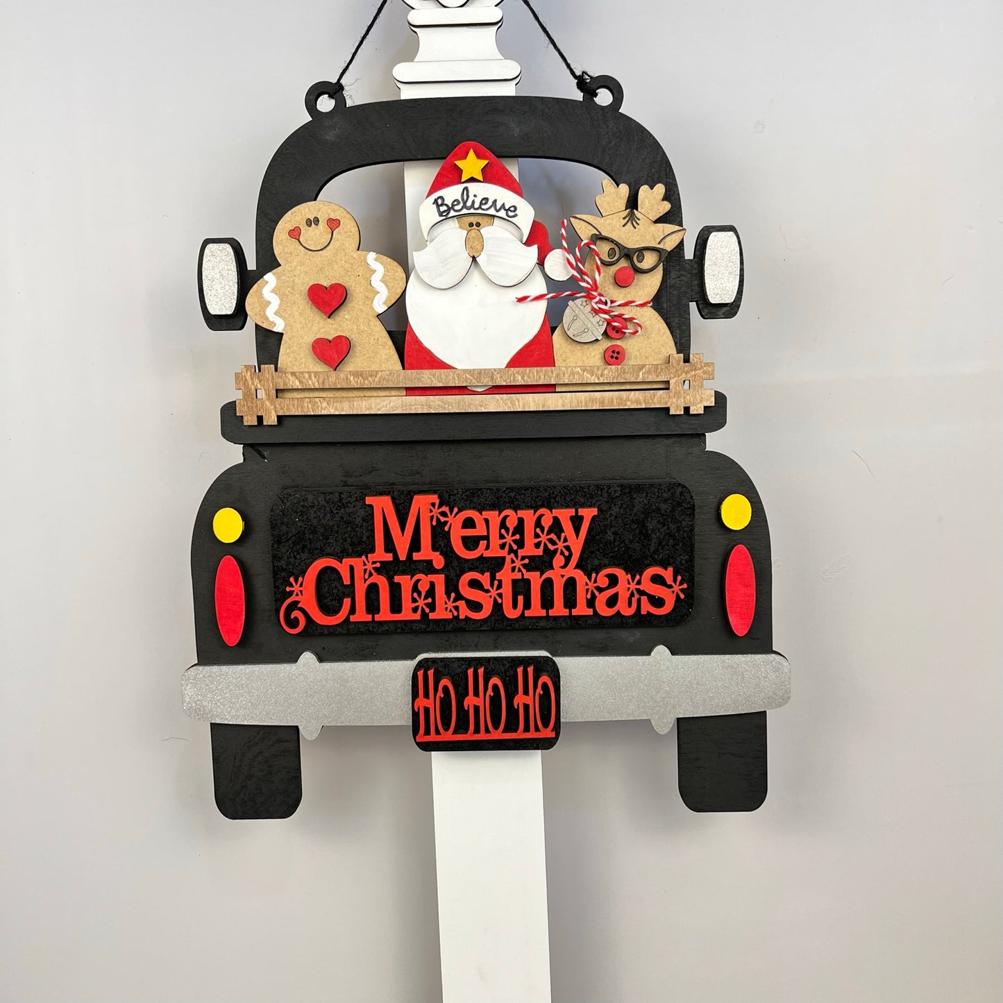 The Merry Christmas Interchangeable Insert DIY home decor kit by Janet's Craft Corner showcases a hand-painted decorative Christmas sign shaped like a truck. In the back, you'll find Santa, a gingerbread figure, and a reindeer, along with the phrases "Merry Christmas" and "Ho Ho Ho." The truck is adorned with festive star and heart motifs, making it ideal for interchangeable home decor.