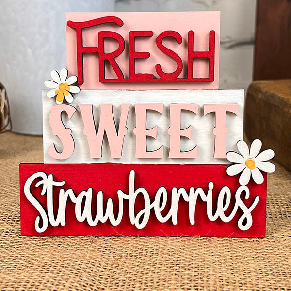 Janet's Craft Corner presents the "Summer Word Stacks," a charming DIY kit to create farmhouse-style decor. Assemble these wooden blocks with burlap that spell out "Fresh Sweet Strawberries" in red, pink, and white, accented with two daisies on the pink and red blocks for a delightful touch.