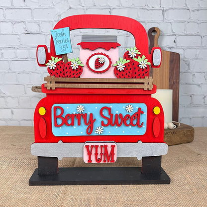 The Berry Sweet Interchangeable Insert from Janet's Craft Corner is a charming DIY home decor kit perfect for farmhouse décor. It features a decorative wooden sign with a red truck carrying strawberries and a jar, labeled "Fresh Berries 25¢," surrounded by daisies and set against a brick wall backdrop. The display also reads "Berry Sweet YUM," making it ideal for adding an interchangeable touch to your home décor.