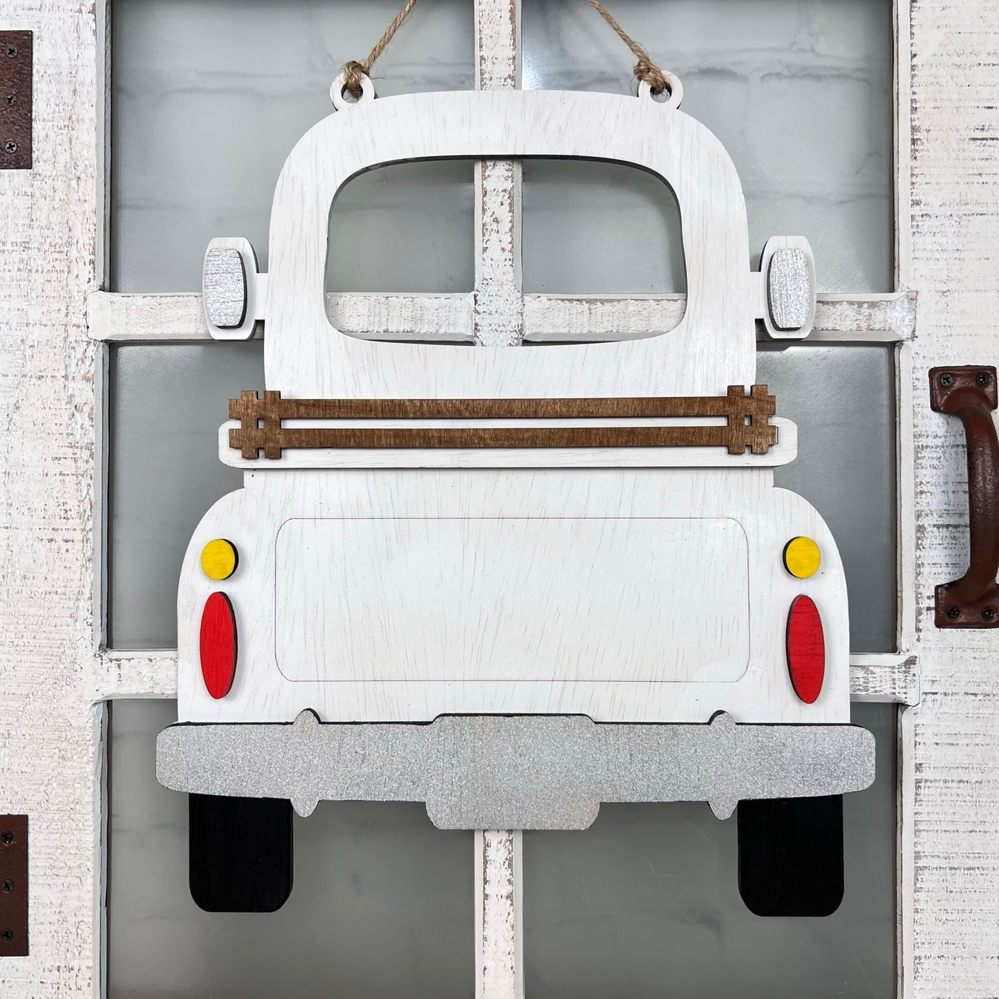 The Antique Truck Interchangeable Base - Painted from Janet's Craft Corner is a wooden décor piece shaped like an antique truck, featuring wood cut-outs for red and yellow tail lights and a brown slat across the rear.