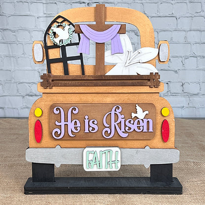 This delightful DIY craft kit from Janet's Craft Corner features a wooden decoration that shows the rear of a truck embellished with Easter motifs. It includes a cross draped with purple cloth, lilies, and a dove in the window. The phrases "He is Risen" and "FAITH" complete this enchanting piece, ideal for interchangeable insert projects.