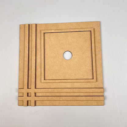 A Farmhouse Trim Interchangeable Squares Holder from Janet's Craft Corner, featuring decorative grooves, a circular center hole, and a design of parallel and perpendicular lines on two sides reminiscent of farmhouse trim, is displayed on a light-colored background.