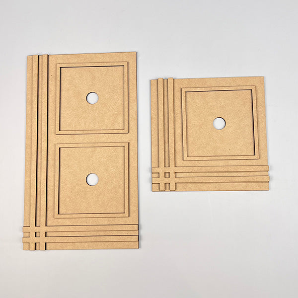 The Farmhouse Trim Interchangeable Squares Holder by Janet's Craft Corner features MDF cutouts with geometric designs and a circular center hole. The larger piece has two stacked, interchangeable squares, while the smaller one includes a single square. Both pieces are adorned with parallel lines on the left side, making them perfect for a creative DIY kit project.