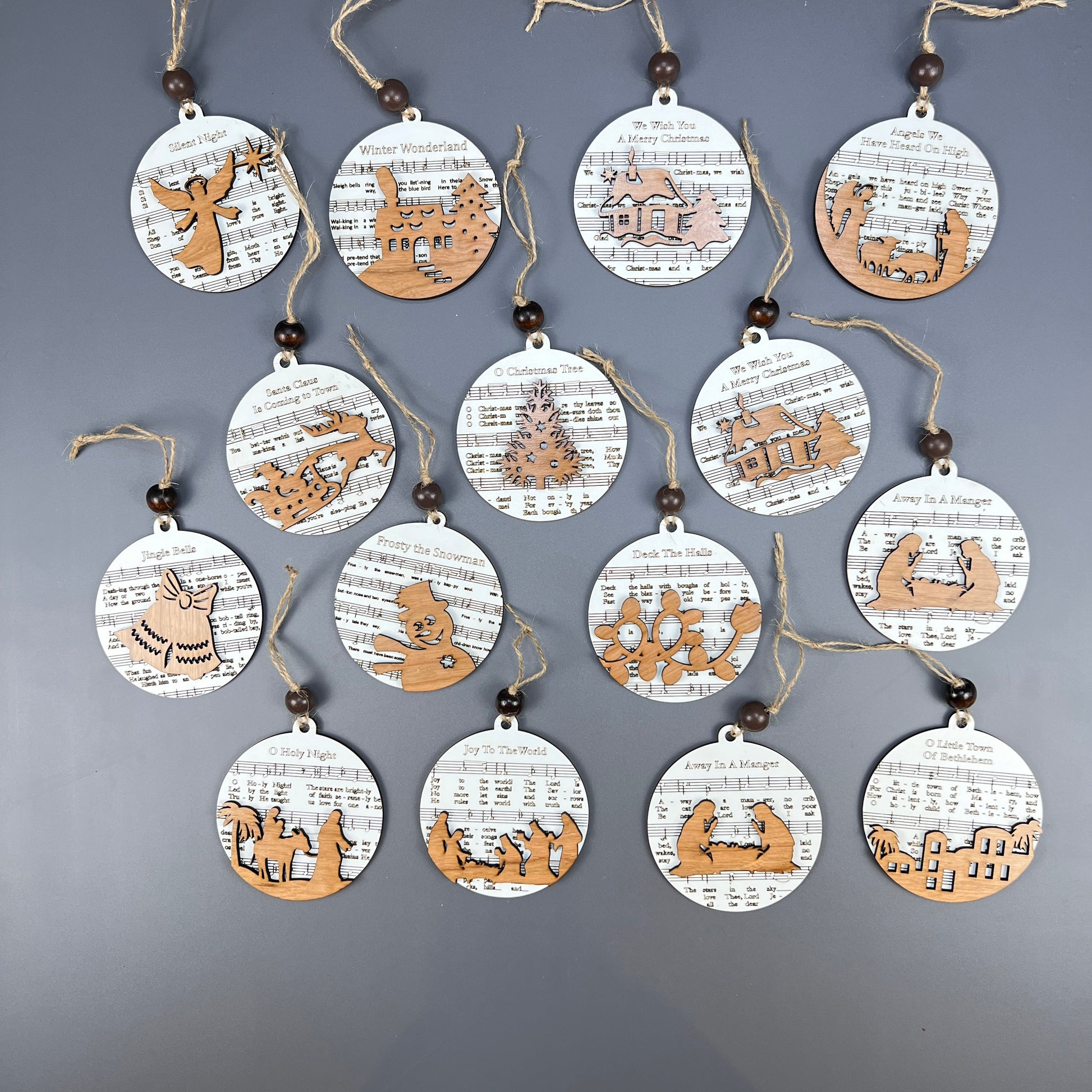 Janet's Craft Corner offers a collection of fifteen Sheet Music Ornaments that exude rustic charm. These circular decorations feature wooden cut-out designs of reindeer, trees, and snowflakes. Perfect for music lovers, each ornament is tied with twine and adorned with a quaint wooden bead.