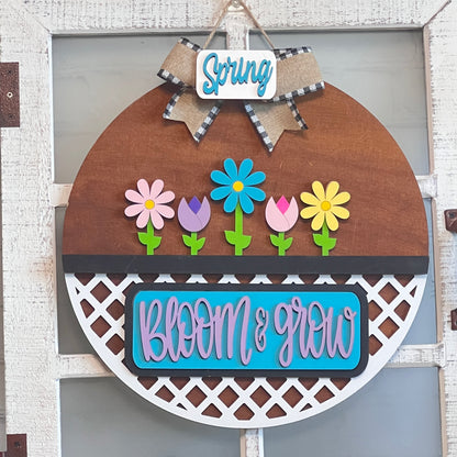 Janet's Craft Corner offers the "Bloom & Grow Interchangeable Insert," a DIY home decor kit with vibrant flowers and text, complemented by a checkered bow and "Spring Blooms" tag, perfect for adding life to your space against any backdrop.