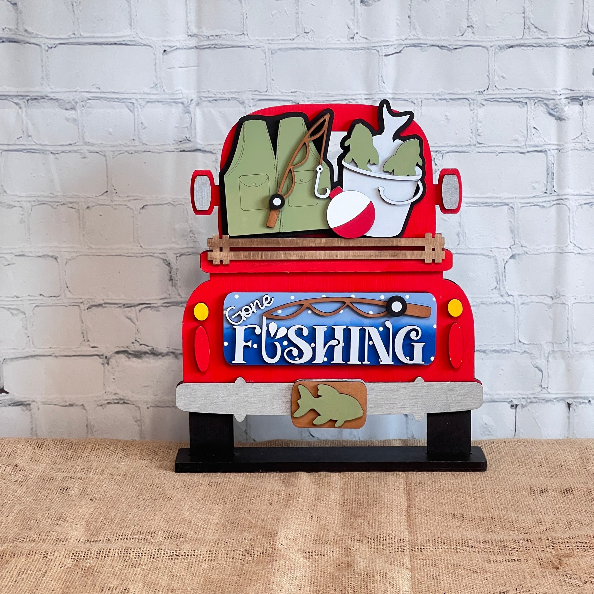 Janet's Craft Corner Gone Fishing Interchangeable Insert is a DIY craft kit (1 set of 3 pieces) featuring a red truck with fishing gear and a “Gone Fishing” tailgate sign—perfect for seasonal home decor.