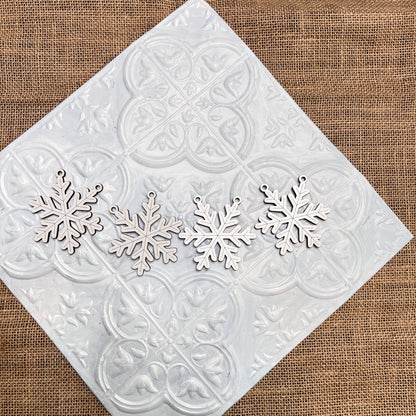 Four Tiered Tray Garlands from Janet's Craft Corner are arranged in a row on a white decorative tile set atop burlap fabric.