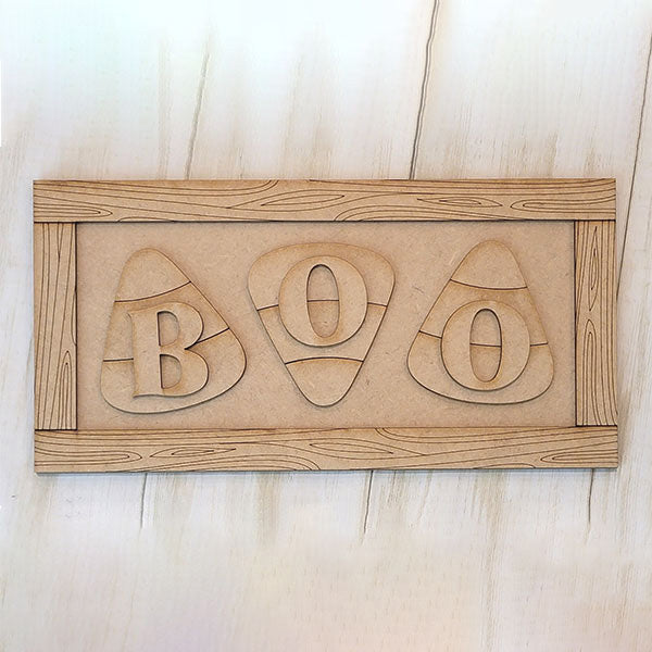 Janet's Craft Corner Boo Candy Corn Shelf Leaner DIY kit features three candy corn shapes with cut-out "B", "O", and "O" letters, a wood grain border, and is perfect for decorating your home this Halloween. Set of 1.
