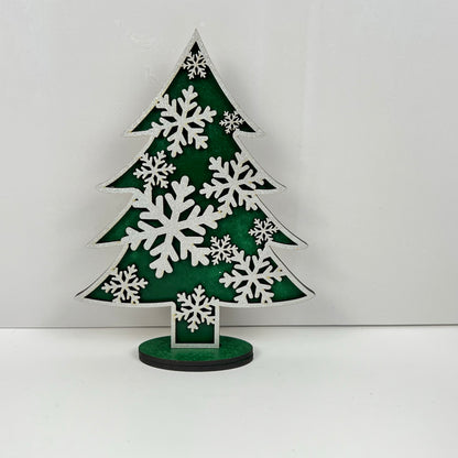The elegant "Standing Christmas Tree Shelf Sitters" by Janet's Craft Corner features a decorative green Christmas tree with large white snowflakes, perfectly complementing a plain white background to enhance your holiday decor or add charm to any shelf display.