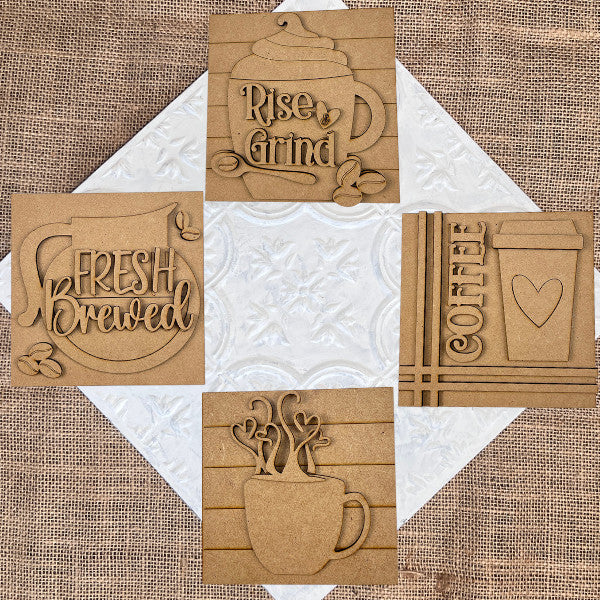 Janet's Craft Corner Coffee Swappable Squares DIY kit features five wooden squares with engraved mugs, beans, and phrases like "Fresh Brewed"—perfect coffee-themed seasonal home decor displayed on burlap.