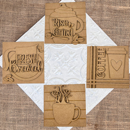 Janet's Craft Corner Coffee Swappable Squares DIY kit features five wooden squares with engraved mugs, beans, and phrases like "Fresh Brewed"—perfect coffee-themed seasonal home decor displayed on burlap.
