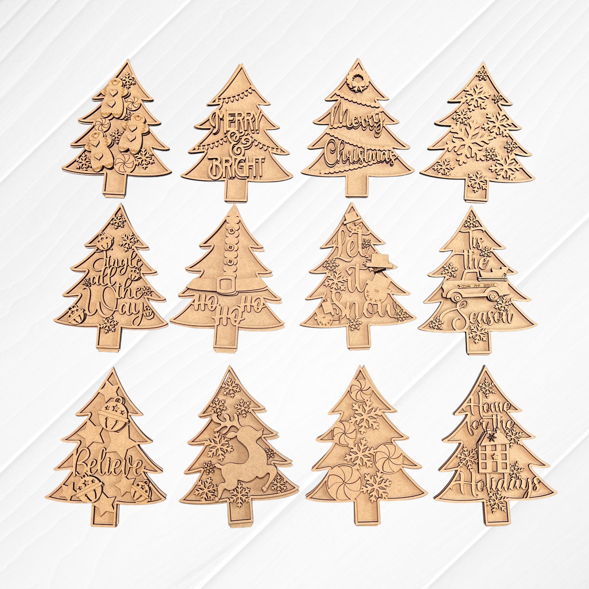 Introducing Janet's Craft Corner's Standing Christmas Tree Shelf Sitters – a set of twelve charming wooden ornaments ideal for holiday decor. Each piece is intricately engraved with unique designs and festive messages like "Merry & Bright," "Let It Snow," and "Believe." These beautifully crafted items are showcased on a white wooden background, ready to elevate your shelf display.