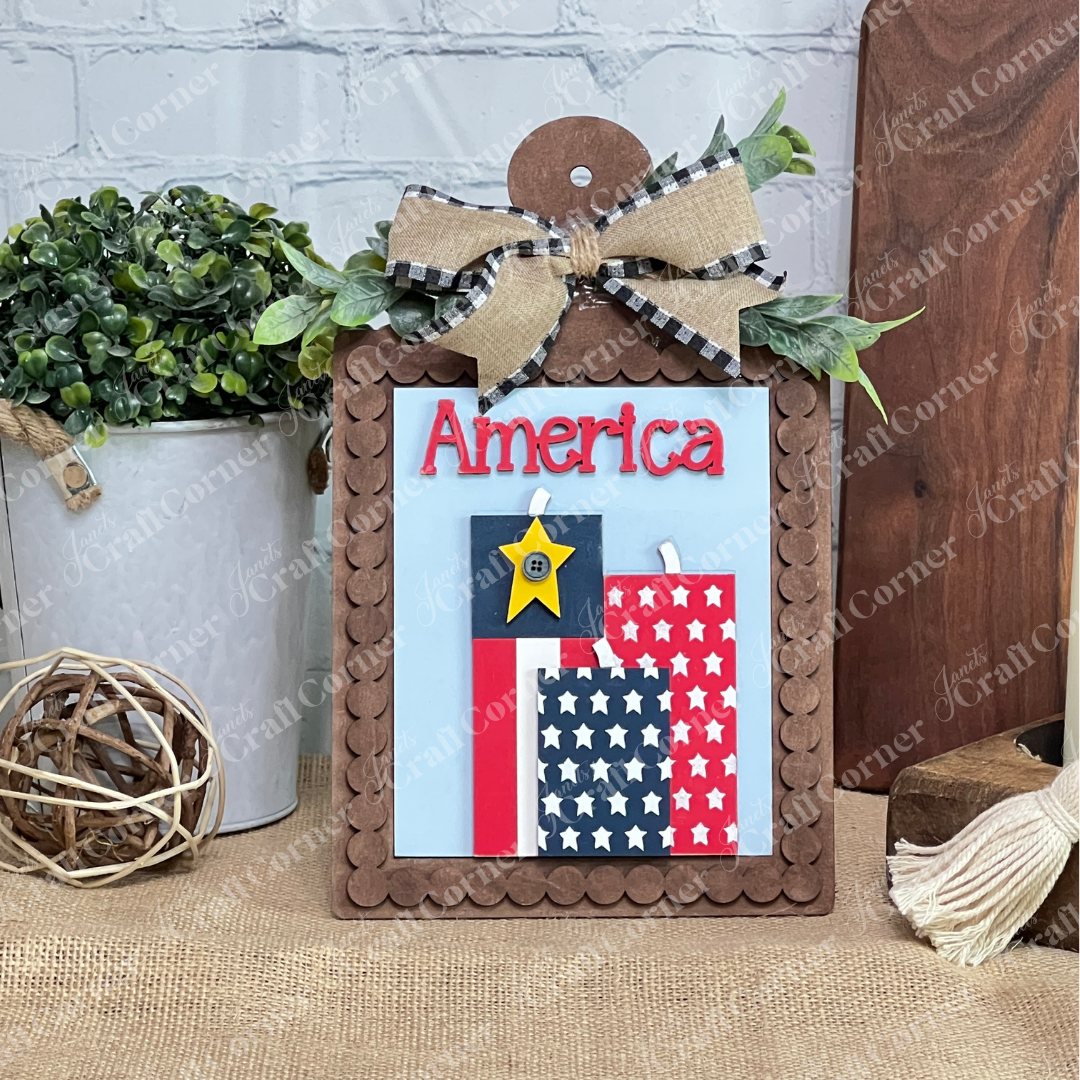 Janet's Craft Corner Patriotic Farmhouse Signs DIY craft kit features a wooden sign with “America” in red, gingham and burlap bow, star blocks, greenery, and rustic accents—perfect for tiered tray decor. Set of 1.