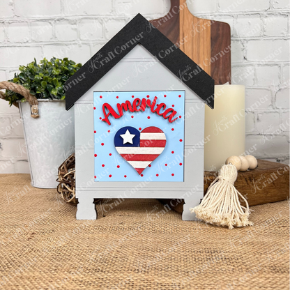 The Patriotic Squares DIY craft kit from Janet's Craft Corner features a house-shaped wooden sign with a heart in an American flag design, red polka dots, and "America" script—perfect for Independence Day décor on tables or with farmhouse accents.