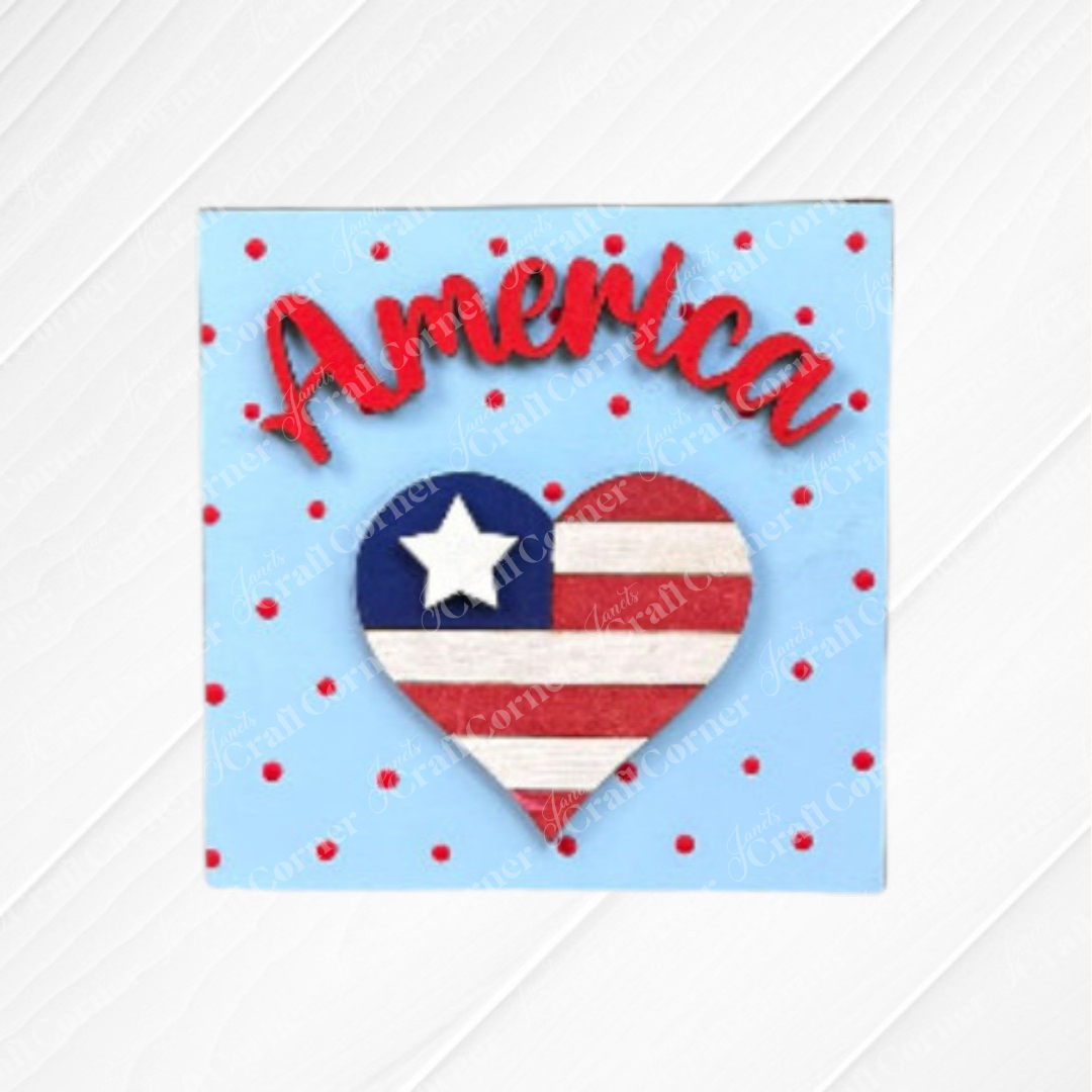 A square sign with a blue background, red polka dots, and "America" in red script above a flag-themed heart—ideal for July 4th. Create it yourself with the Patriotic Squares DIY kit from Janet's Craft Corner.