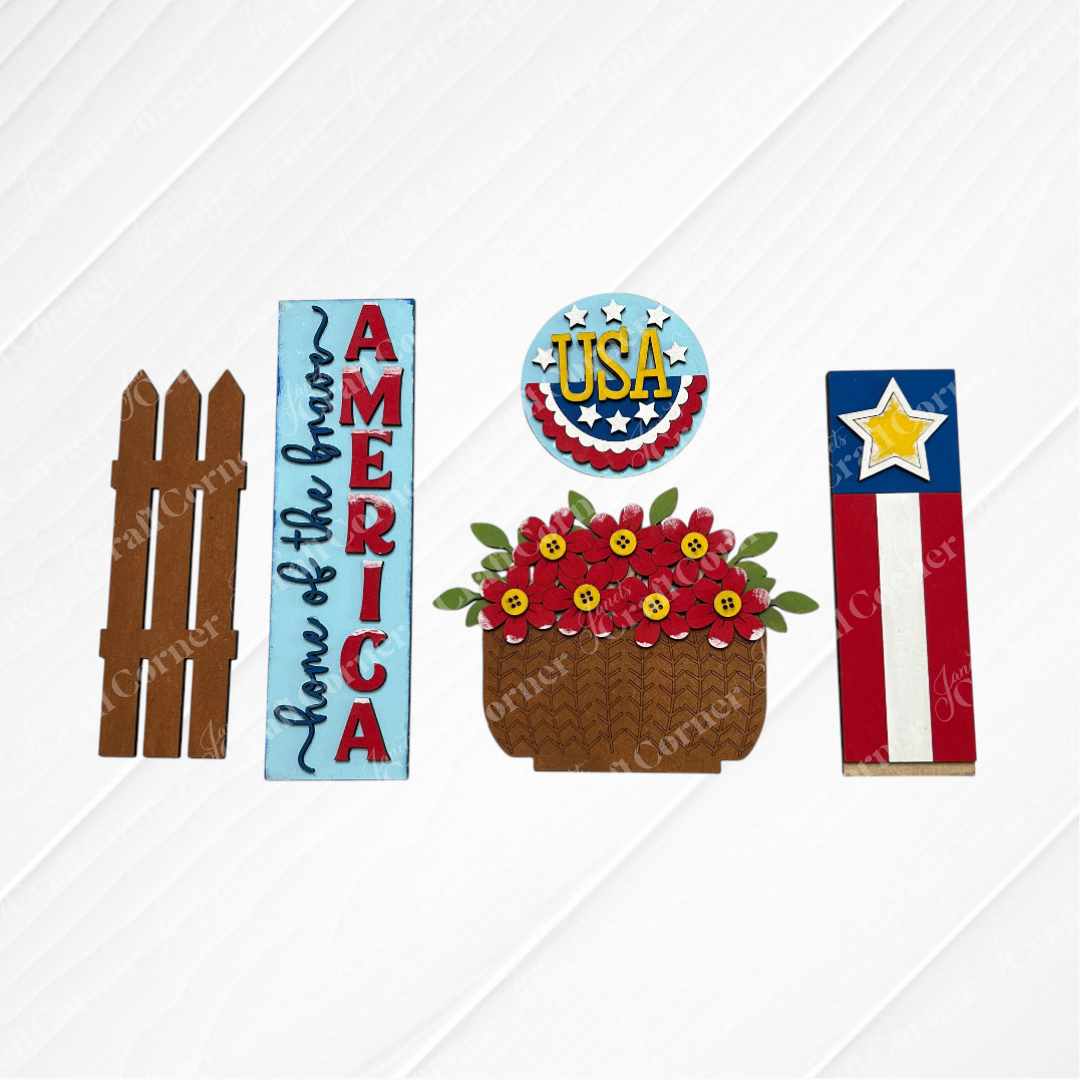 Janet's Craft Corner America Interchangeable Porch Set: features a brown picket fence, blue “America” and “Home of the Brave” sign, DIY round USA star sign, floral basket, and red-white-blue board with star—perfect for patriotic home decor.